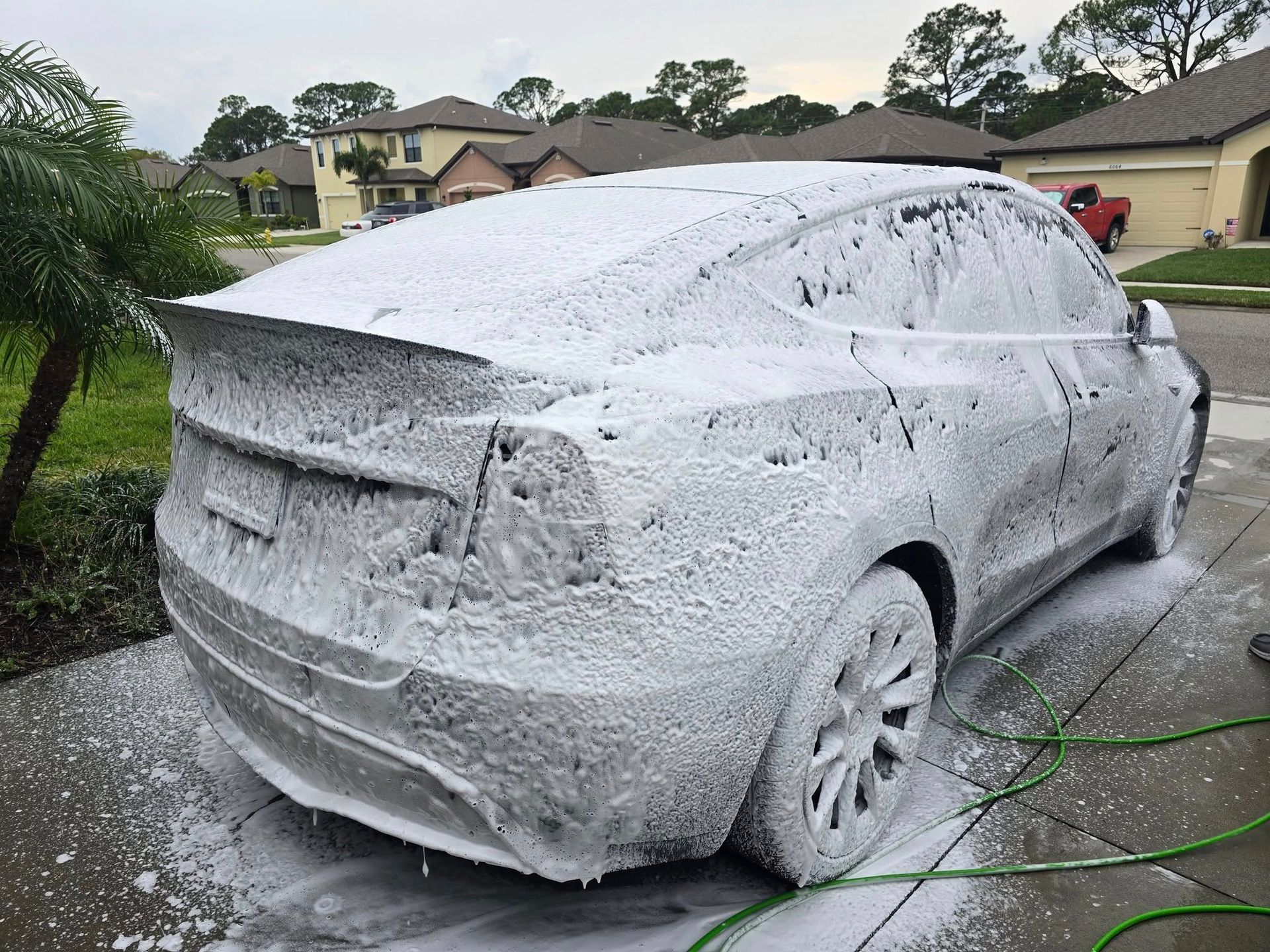 A tesla model y is covered in foam in a driveway.