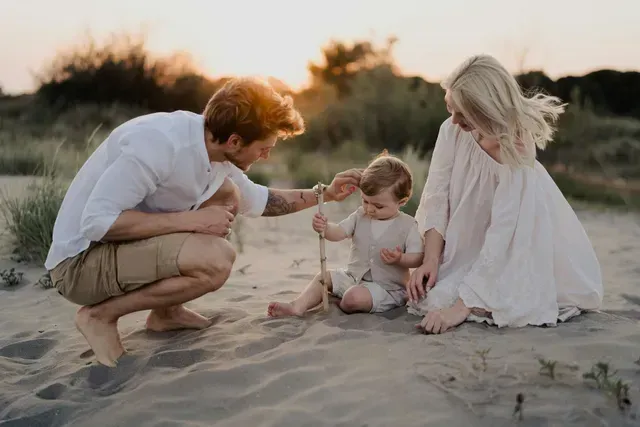 A family is playing in the sand on the beach.