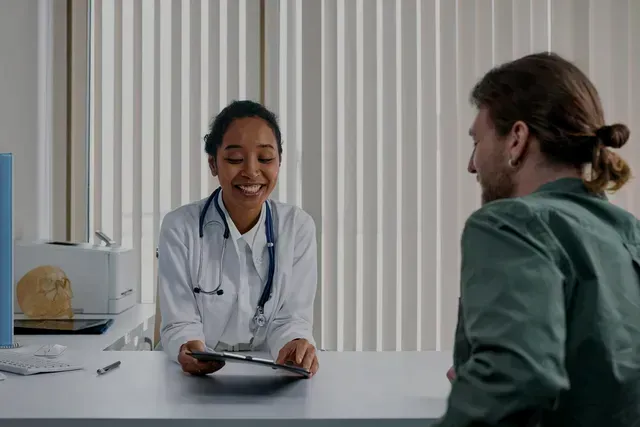 A doctor is sitting at a table talking to a patient.
