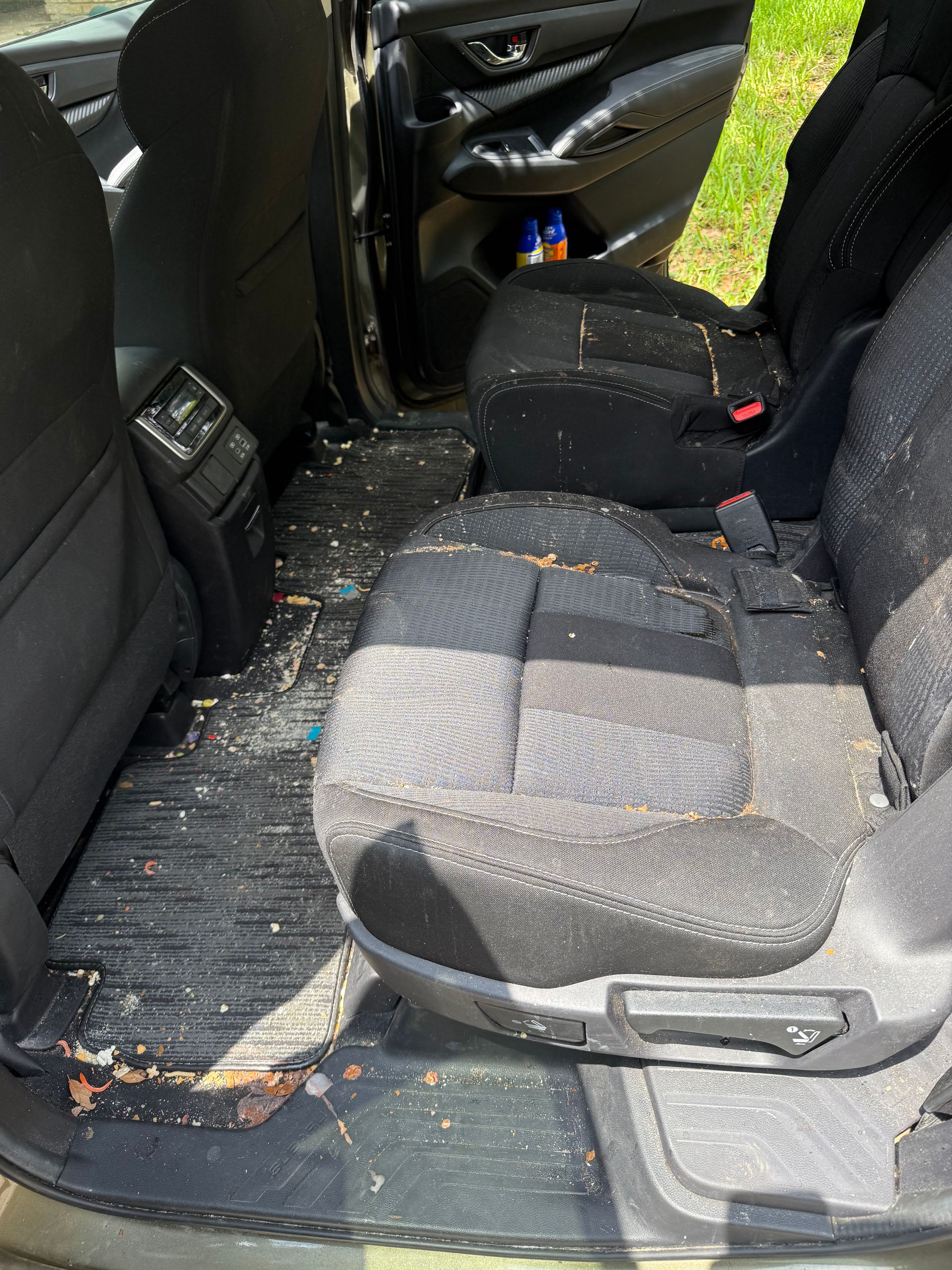 Dirty car interior with food debris on seats and floor.