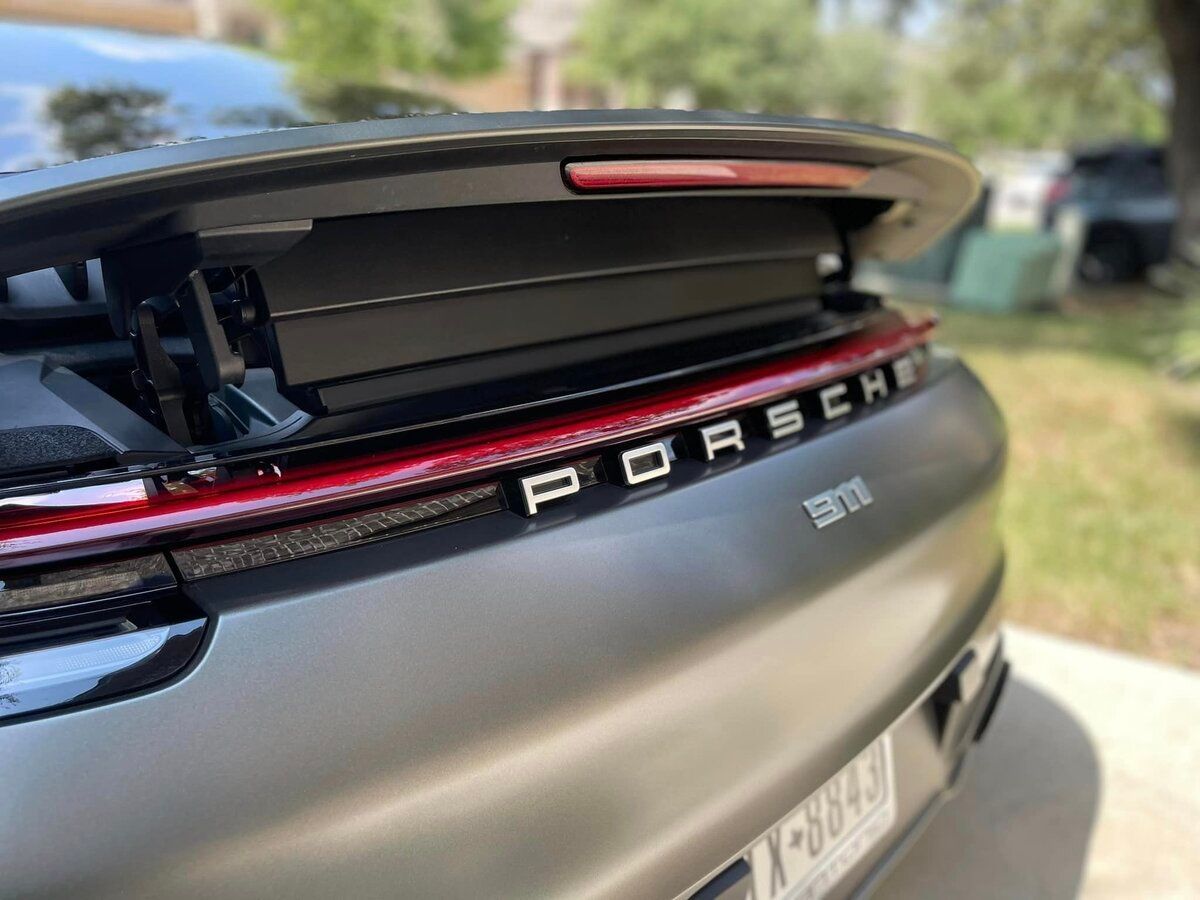 A silver tesla model s is parked in front of a brick house.