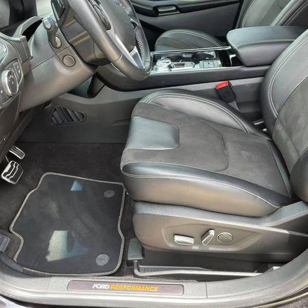 The inside of a black ford car with the door open