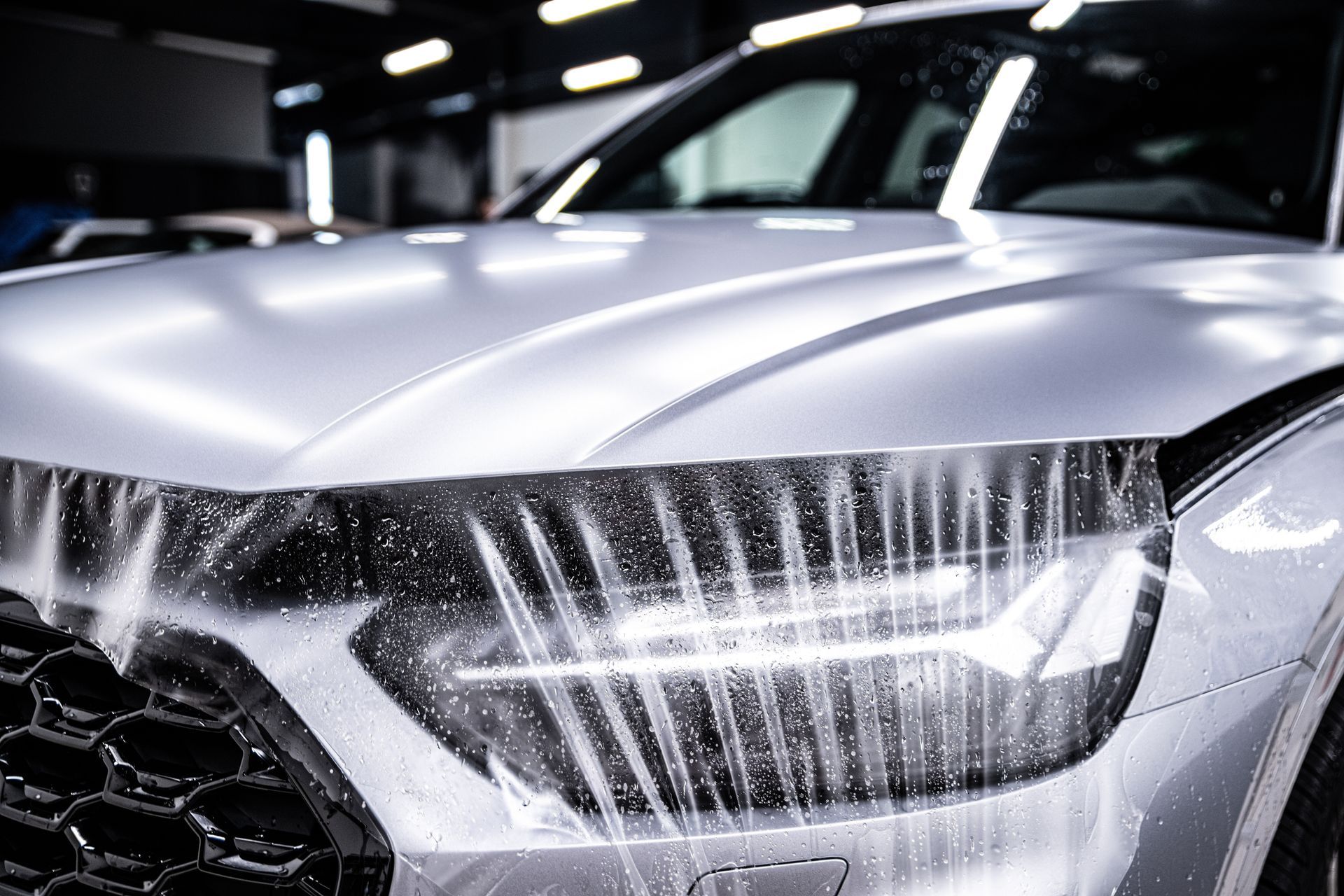 A close up of a silver car being washed in a garage.