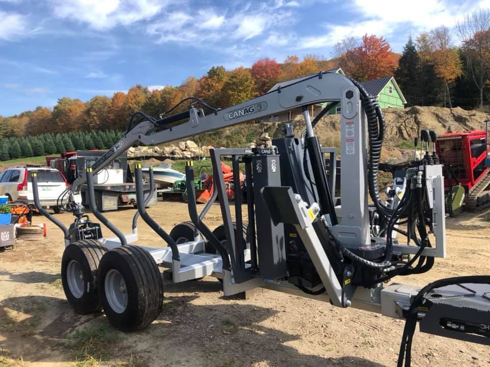 A trailer with a crane attached to it is parked in a dirt field.
