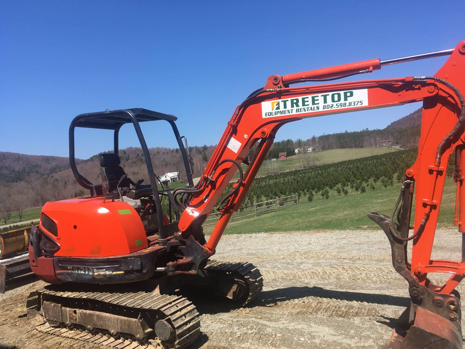 An orange excavator is parked in a dirt field.