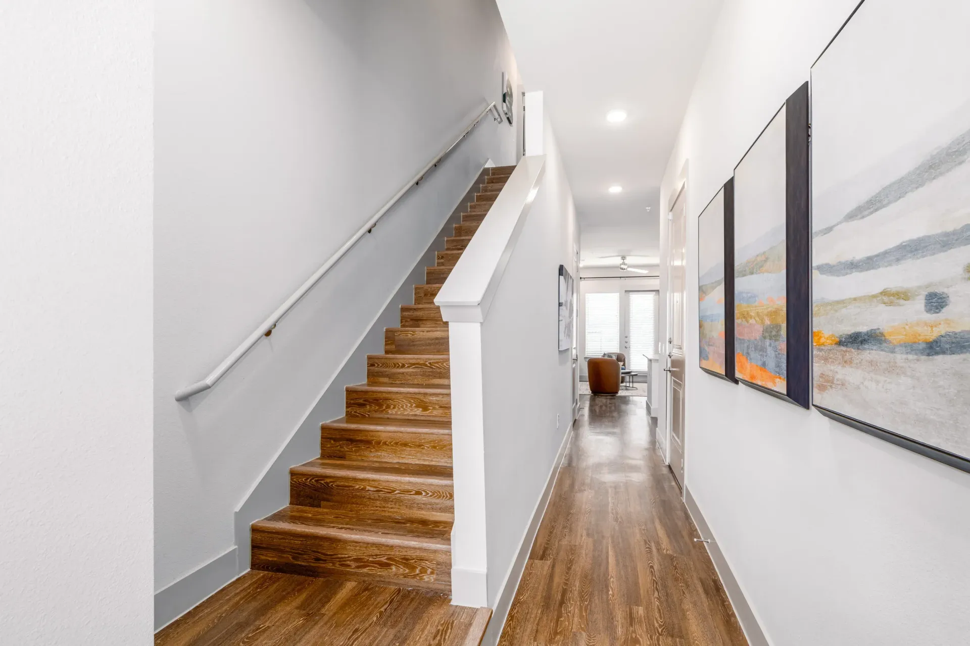 Interior hallway in an apartment with wooden stairs and wall art.