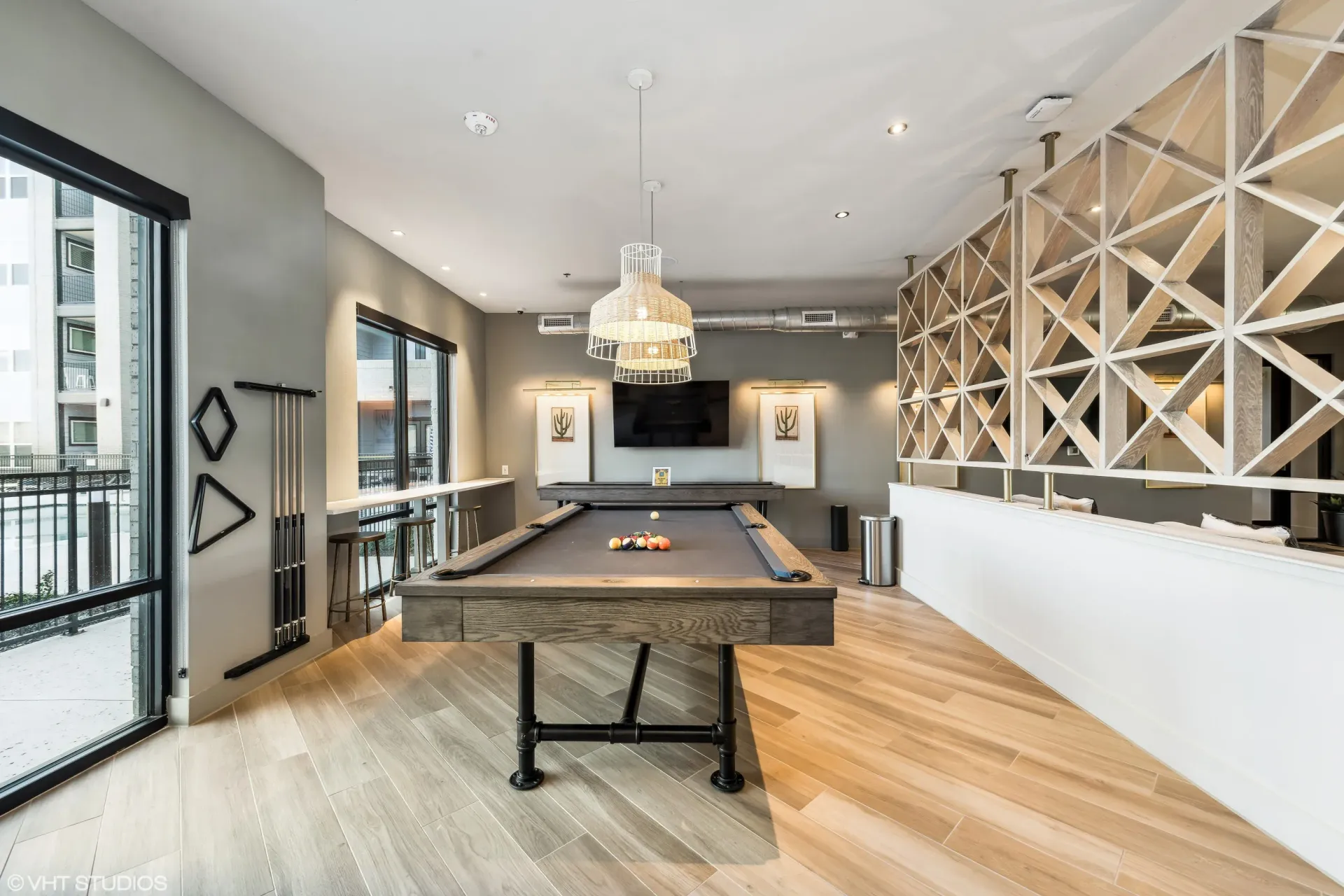 Indoor community billiards room with a pool table, pendant lighting, and lattice divider.