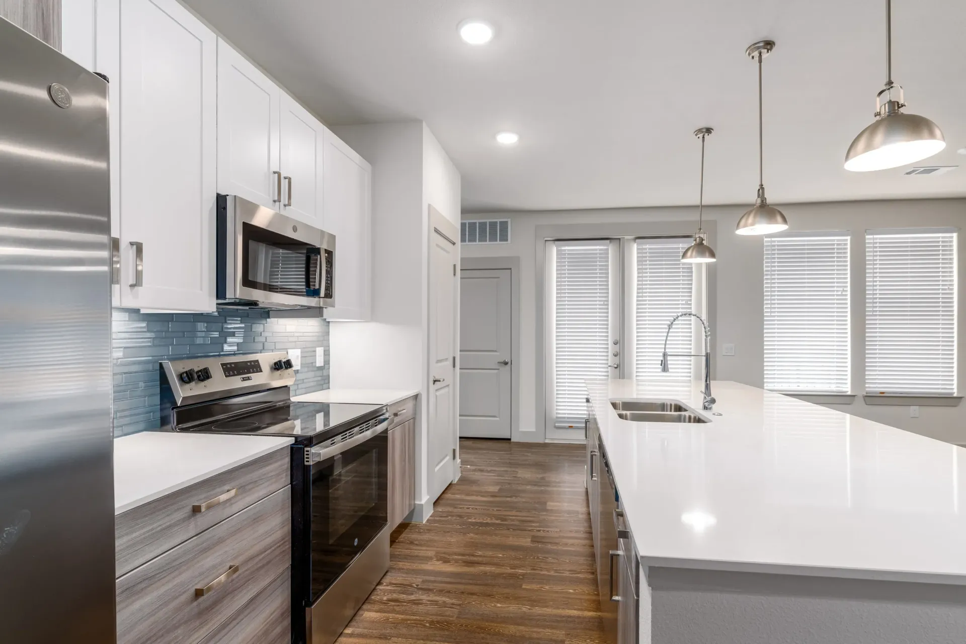Modern apartment kitchen with stainless steel appliances, white cabinets, and a large island.