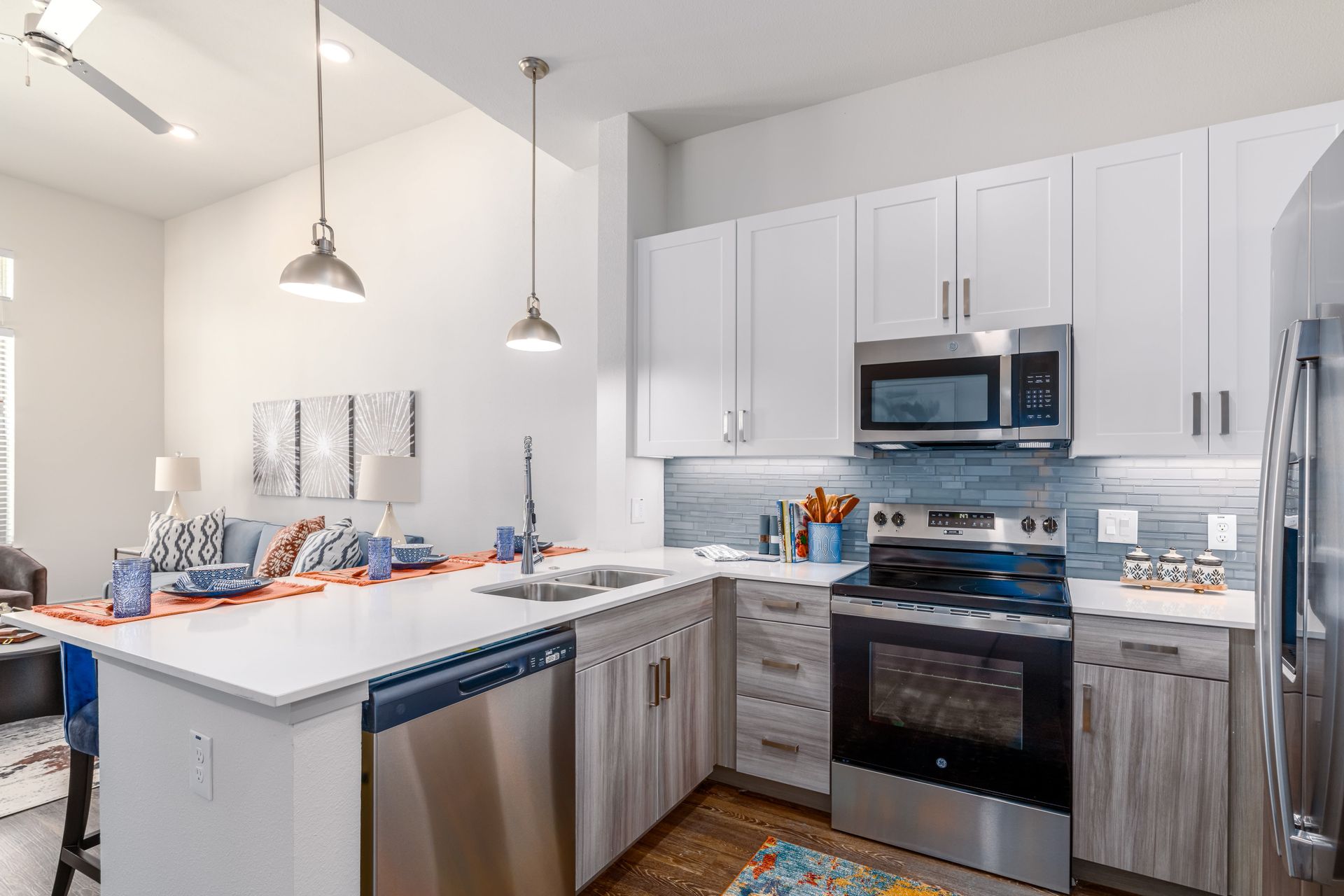 Bright modern kitchen with white cabinets, stainless appliances, and a white island with orange accents