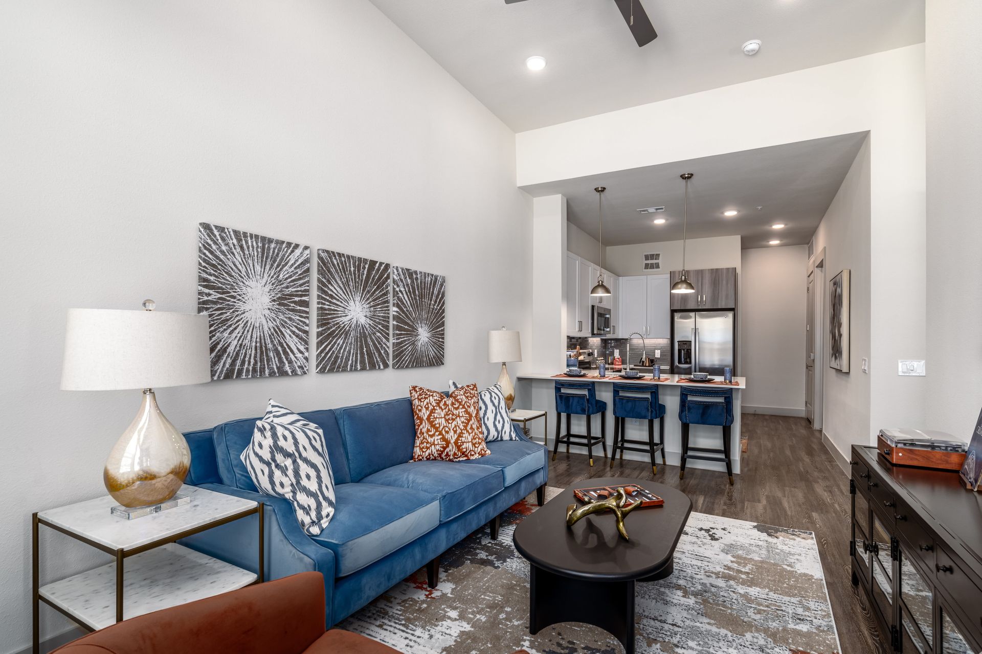 Modern living room with blue sofa, patterned rug, and open kitchen beyond