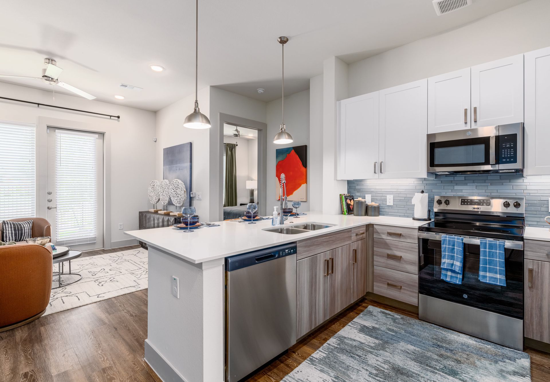 Modern kitchen with white cabinets, gray island, stainless appliances, and open living area beyond.