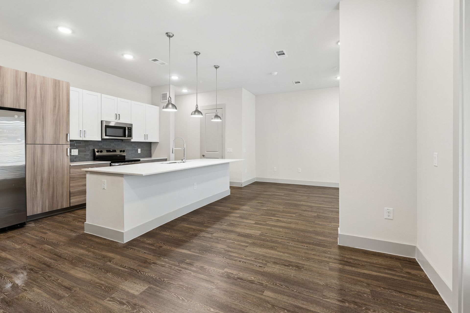 Bright modern kitchen with white cabinets, a large island, and wood-look flooring