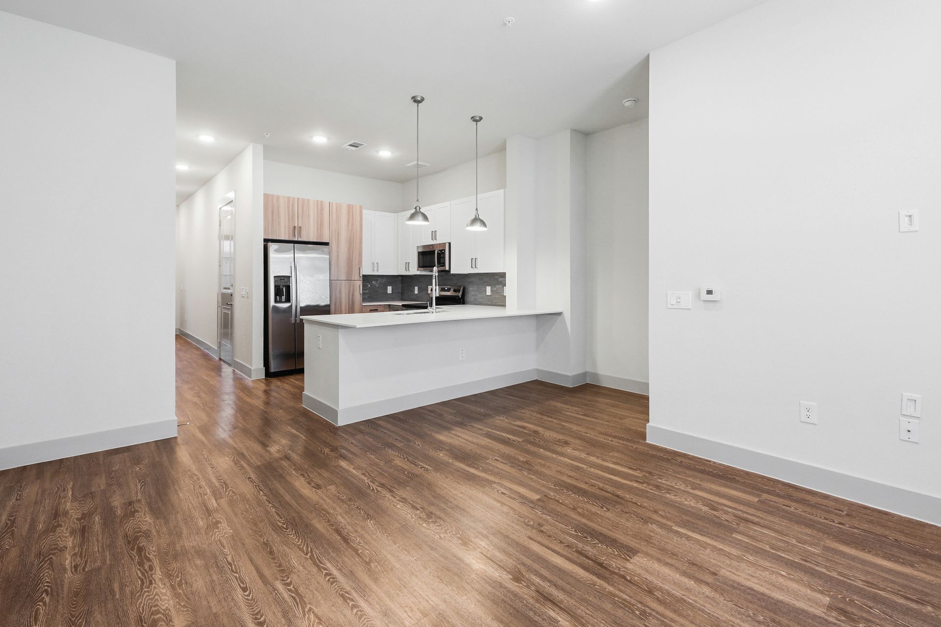 Empty modern apartment living area with wood floors and white kitchen island