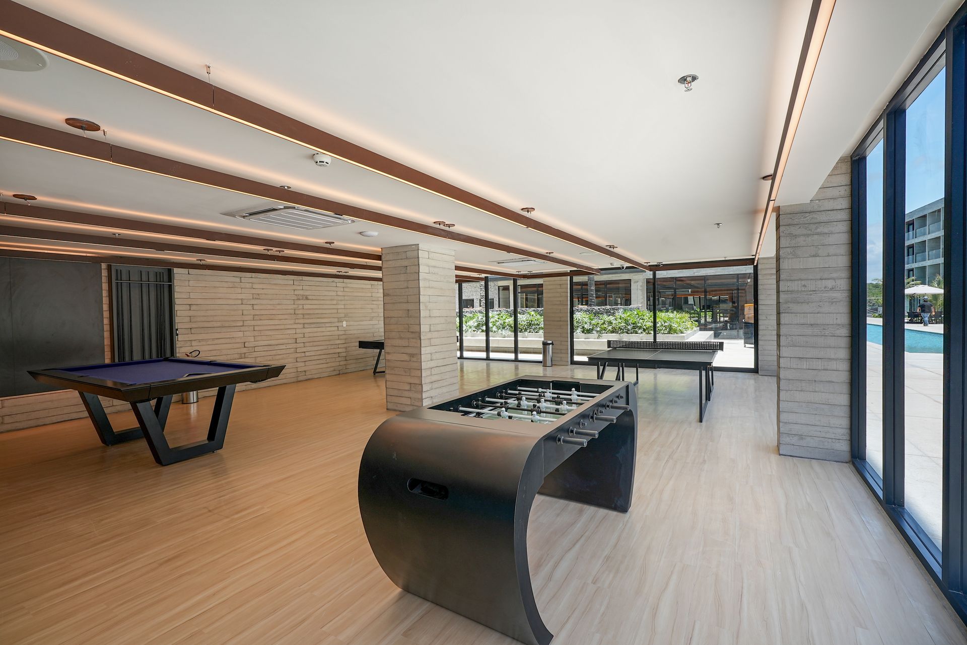 Há uma mesa de sinuca e uma mesa de pebolim na sala.