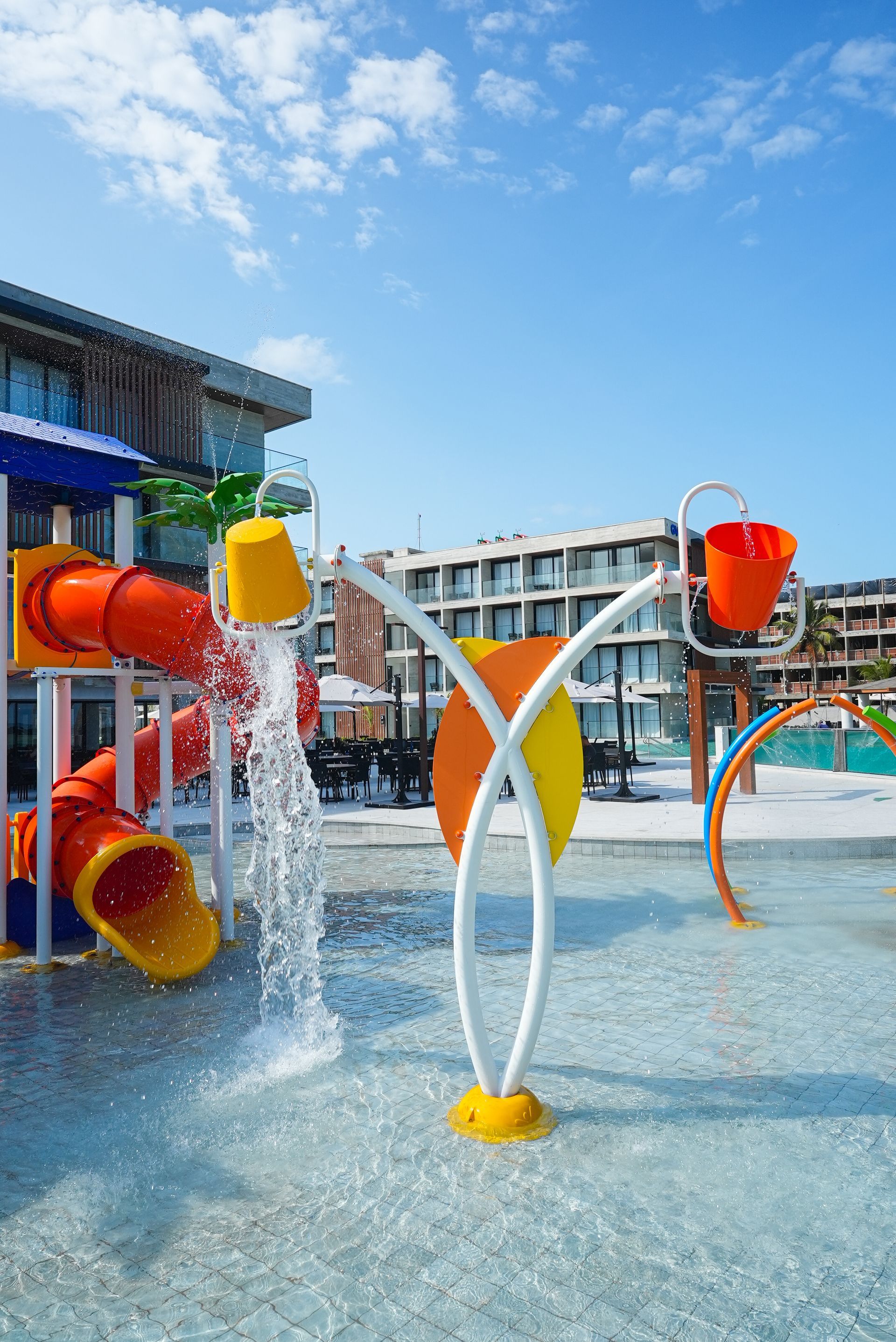 Um sofá circular está no meio de uma piscina cercada por palmeiras.