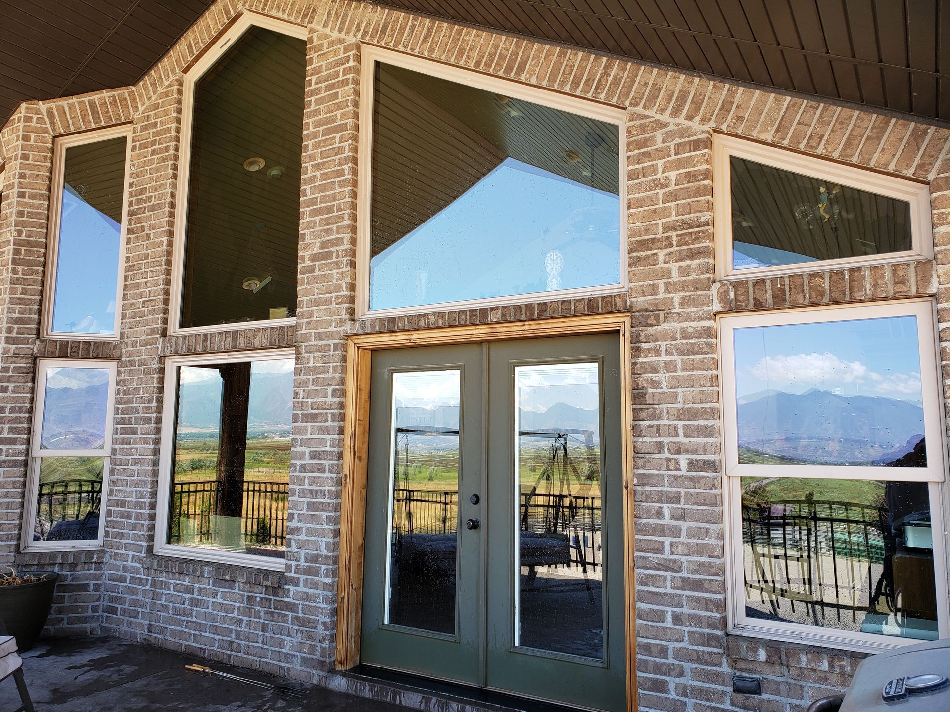 Brick house with large windows and double doors, reflecting sky and mountains.