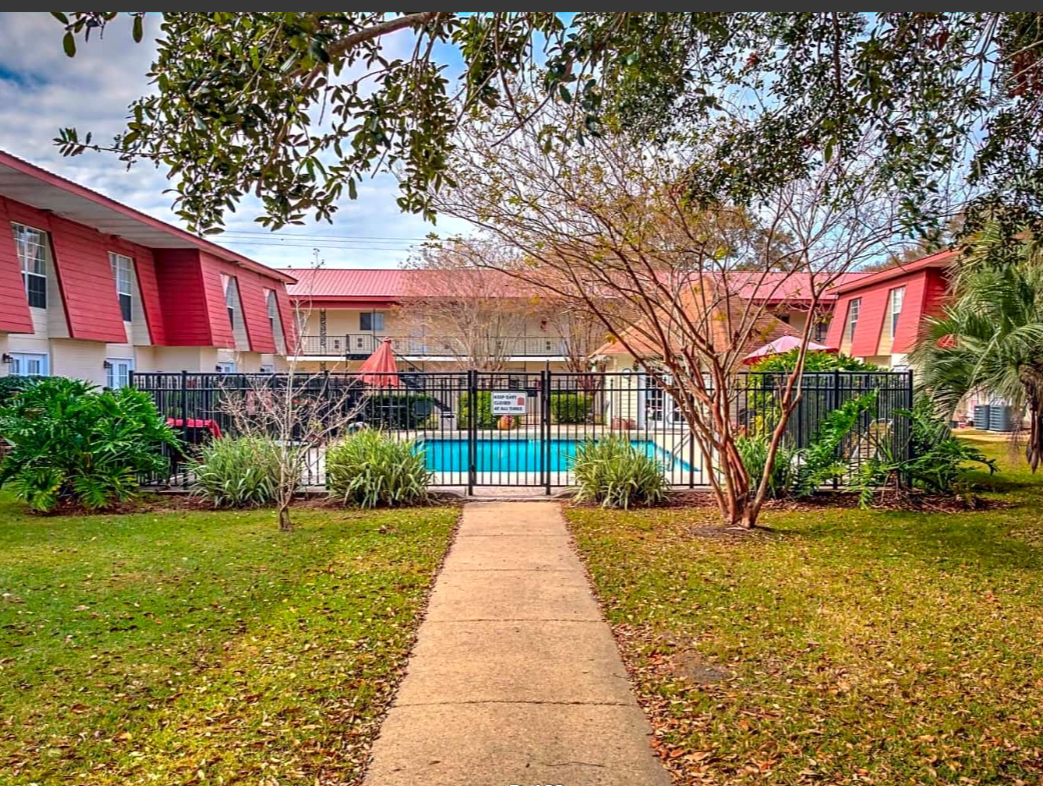 A walkway leading to a swimming pool in front of a building.