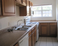 A kitchen with two sinks a stove and a window