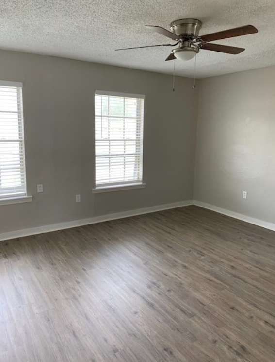 An empty living room with hardwood floors and a ceiling fan.