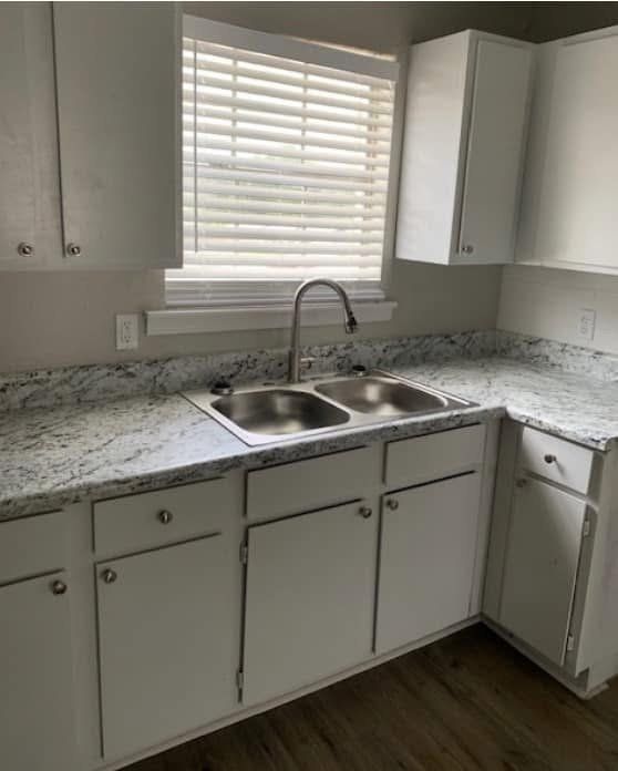 A kitchen with two sinks , white cabinets and a window.