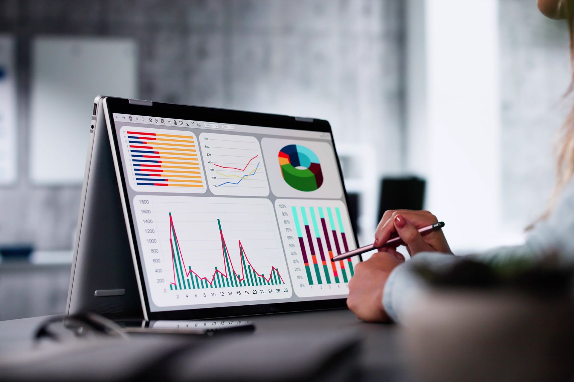 Woman using a laptop displaying financial charts and graphs; indoors.