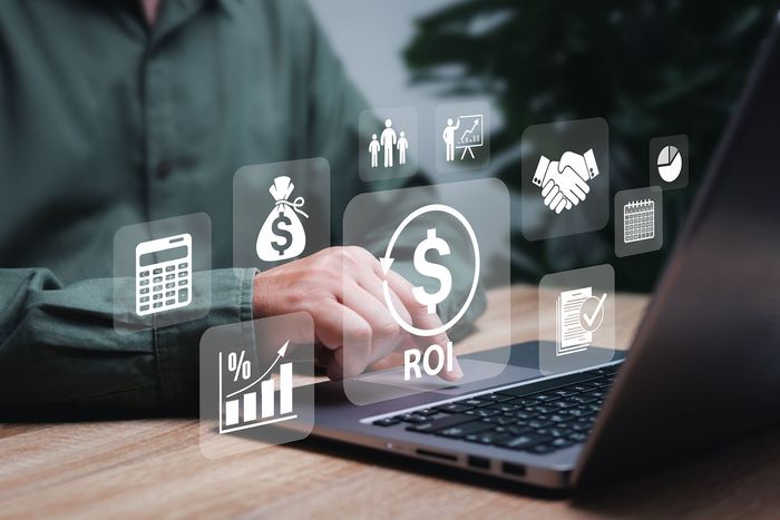 Person using laptop with ROI graphic overlays, indicating financial analysis and investment.