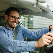 Family smiles inside a car, driving on a sunny day.