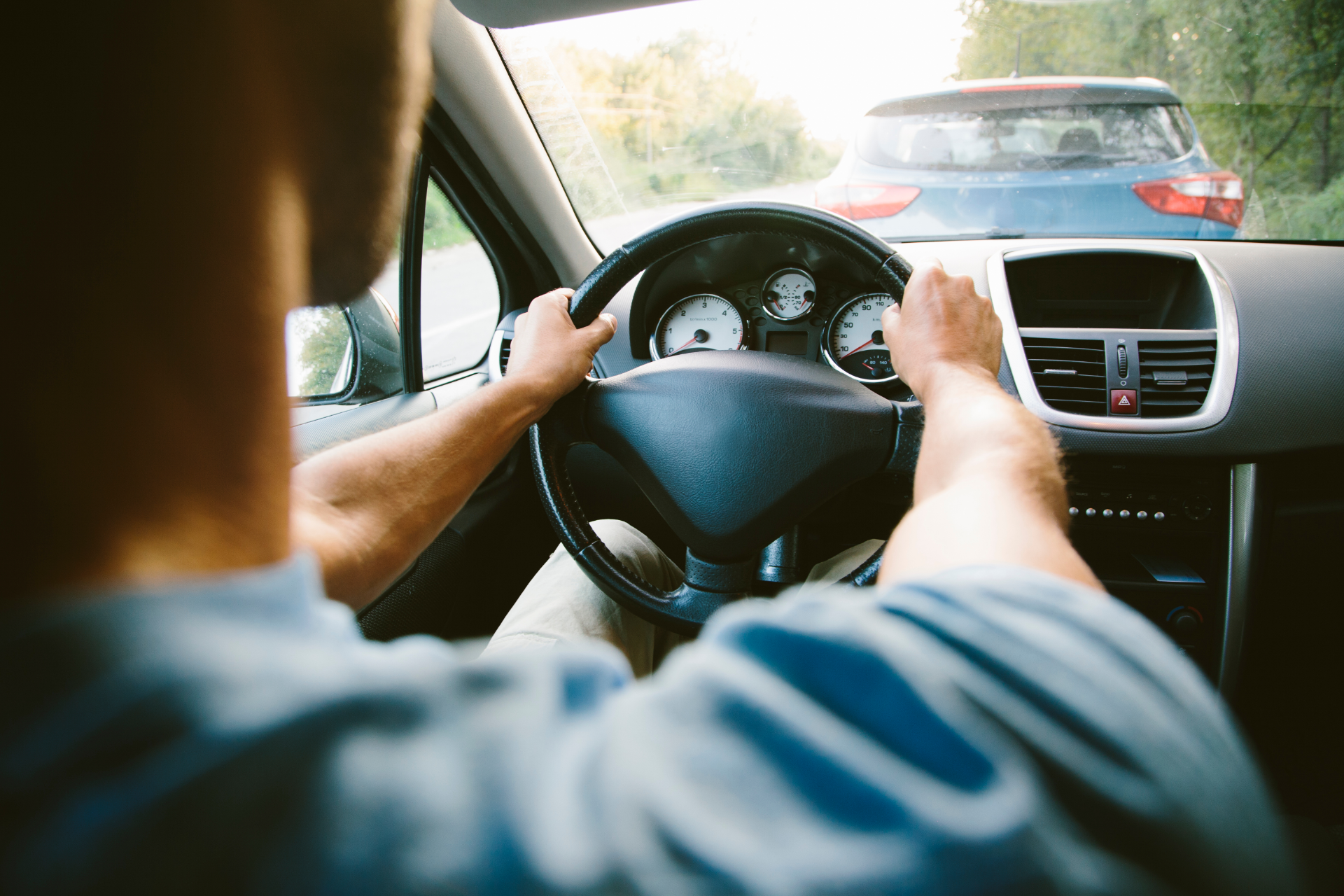 Man in plaid shirt smiles at child from car window.