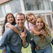 Family smiles inside a car, driving on a sunny day.