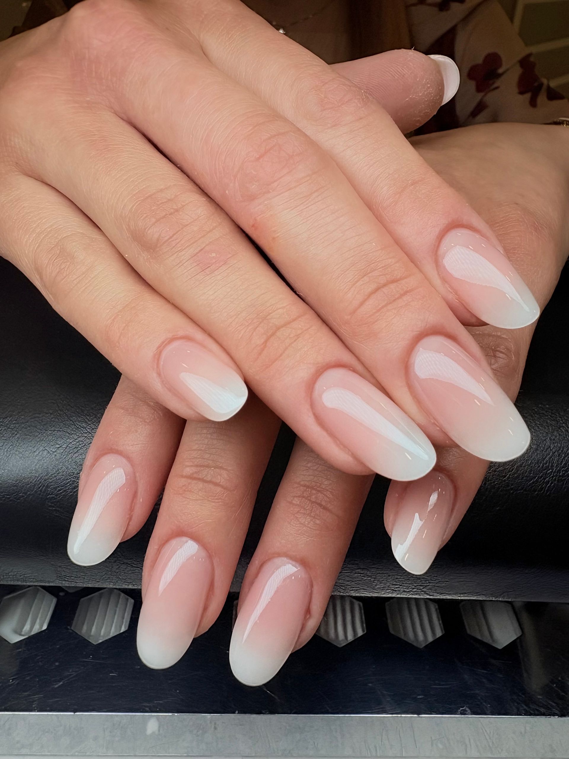 Mani con unghie ovali sfumate rosa chiaro e bianco.