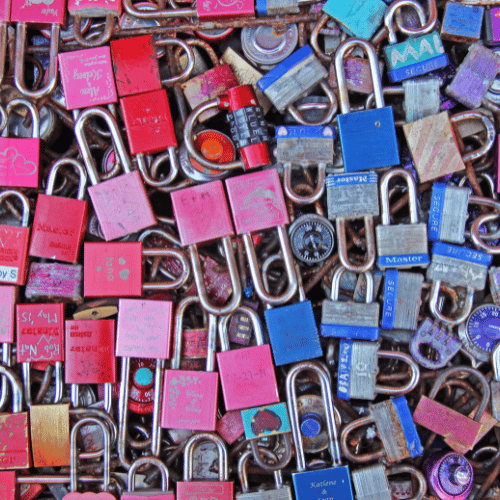 Close-up of colorful love locks attached together, red, pink, blue, and metal tones.