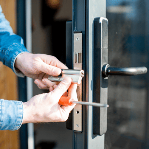 Person installing a lock cylinder on a modern door with a screwdriver.