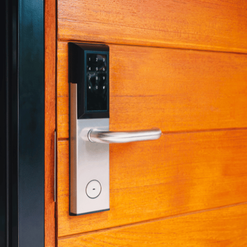 Modern smart lock on a wooden door, with a silver handle and keypad.