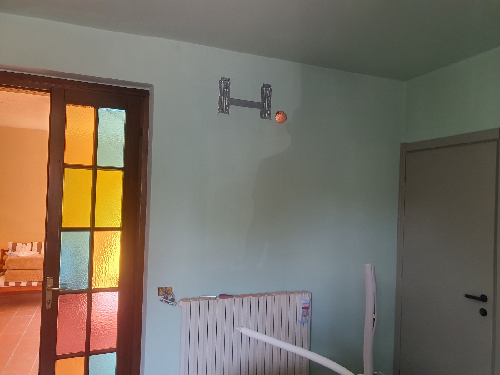 Una stanza con una porta a vetri colorati e un termosifone