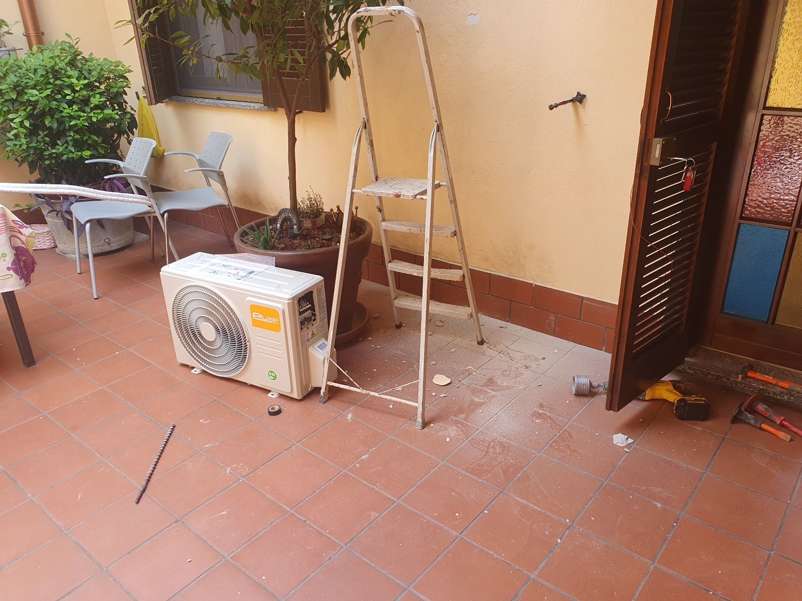 Un condizionatore è appoggiato su un pavimento piastrellato accanto a una scala.