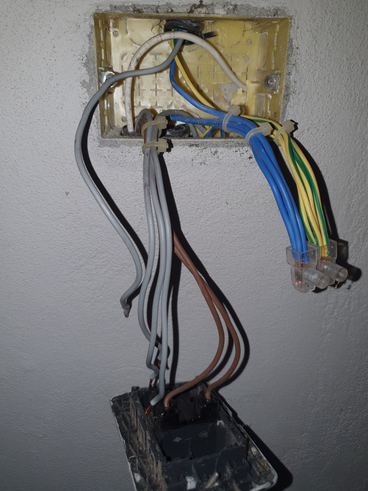 Un mucchio di fili escono da una scatola su un muro.
