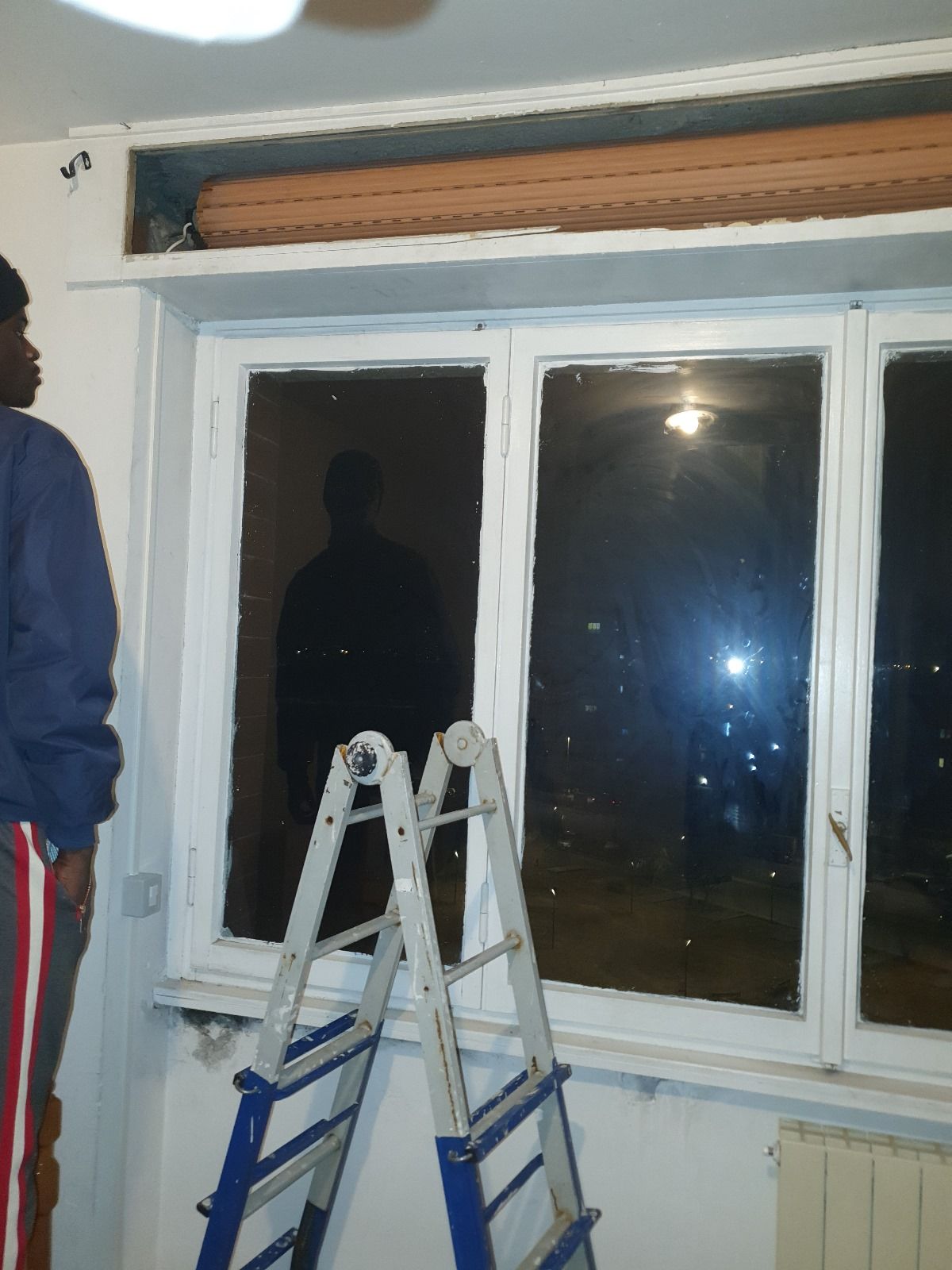 Un uomo in piedi accanto a una scala davanti a una finestra