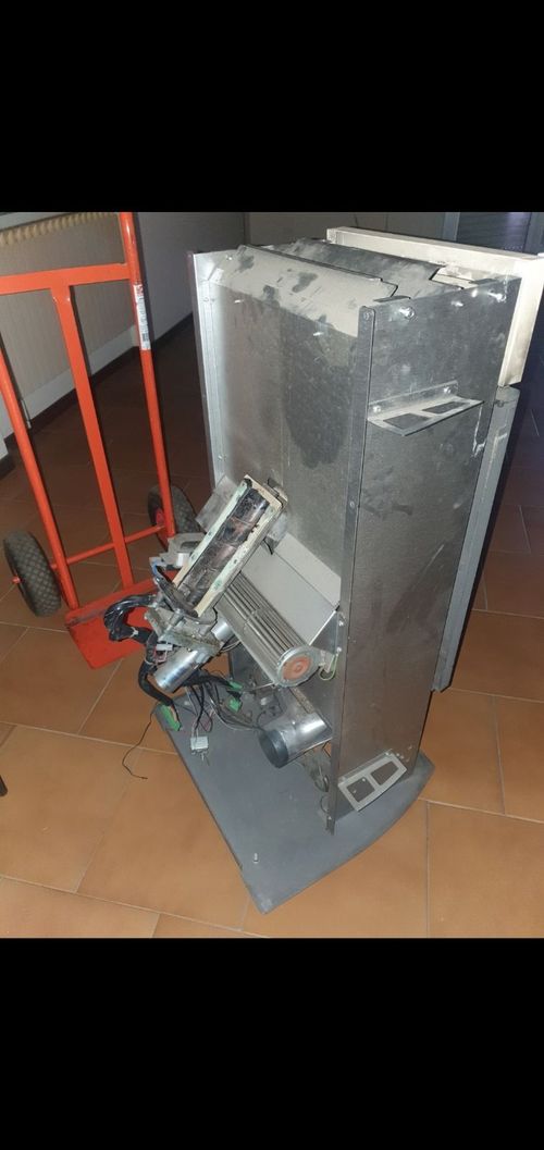 Un frigorifero è appoggiato su un pavimento di legno accanto a un carrello.