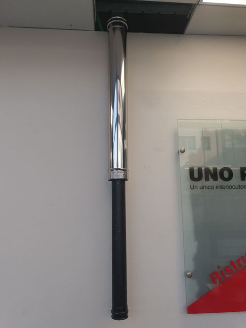Un tubo di acciaio inossidabile è appeso al soffitto accanto a un cartello che dice uno f