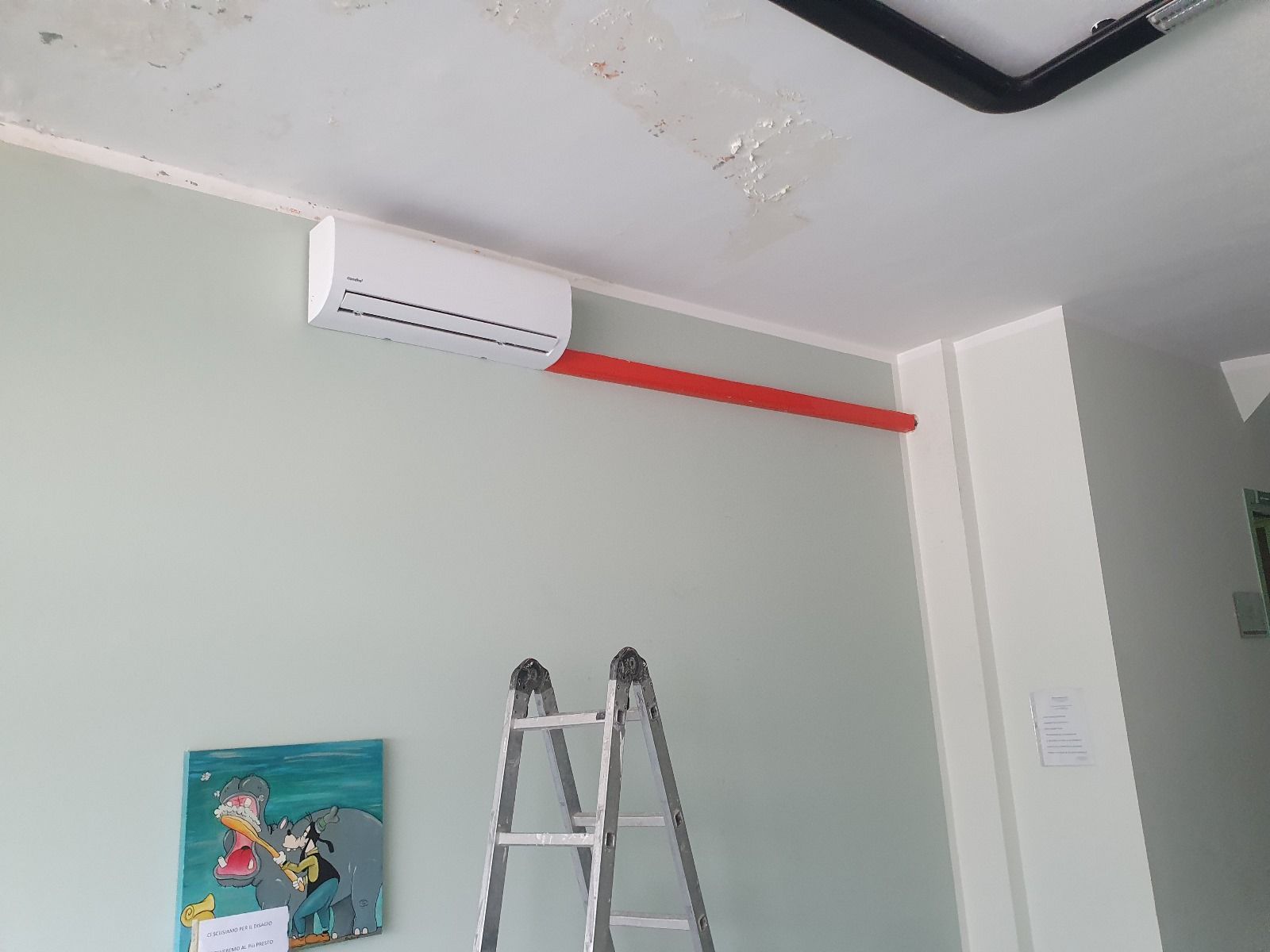 Una stanza con una scala e un condizionatore sul muro.