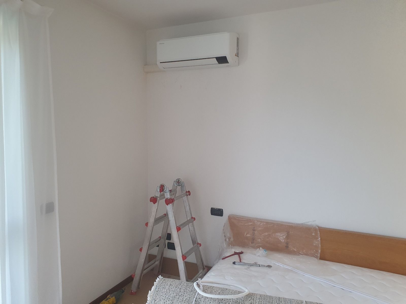 Una camera da letto con un letto, una scala e l'aria condizionata sul muro.