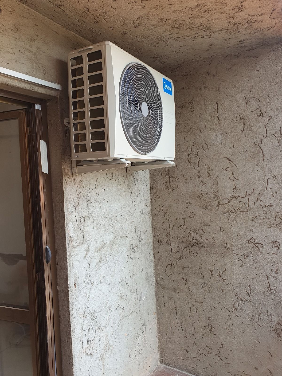 Un condizionatore bianco è appeso alla parete accanto a una porta.