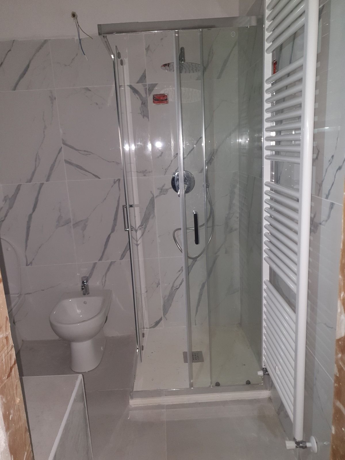 Un bagno con wc, lavandino, doccia e portasciugamani.