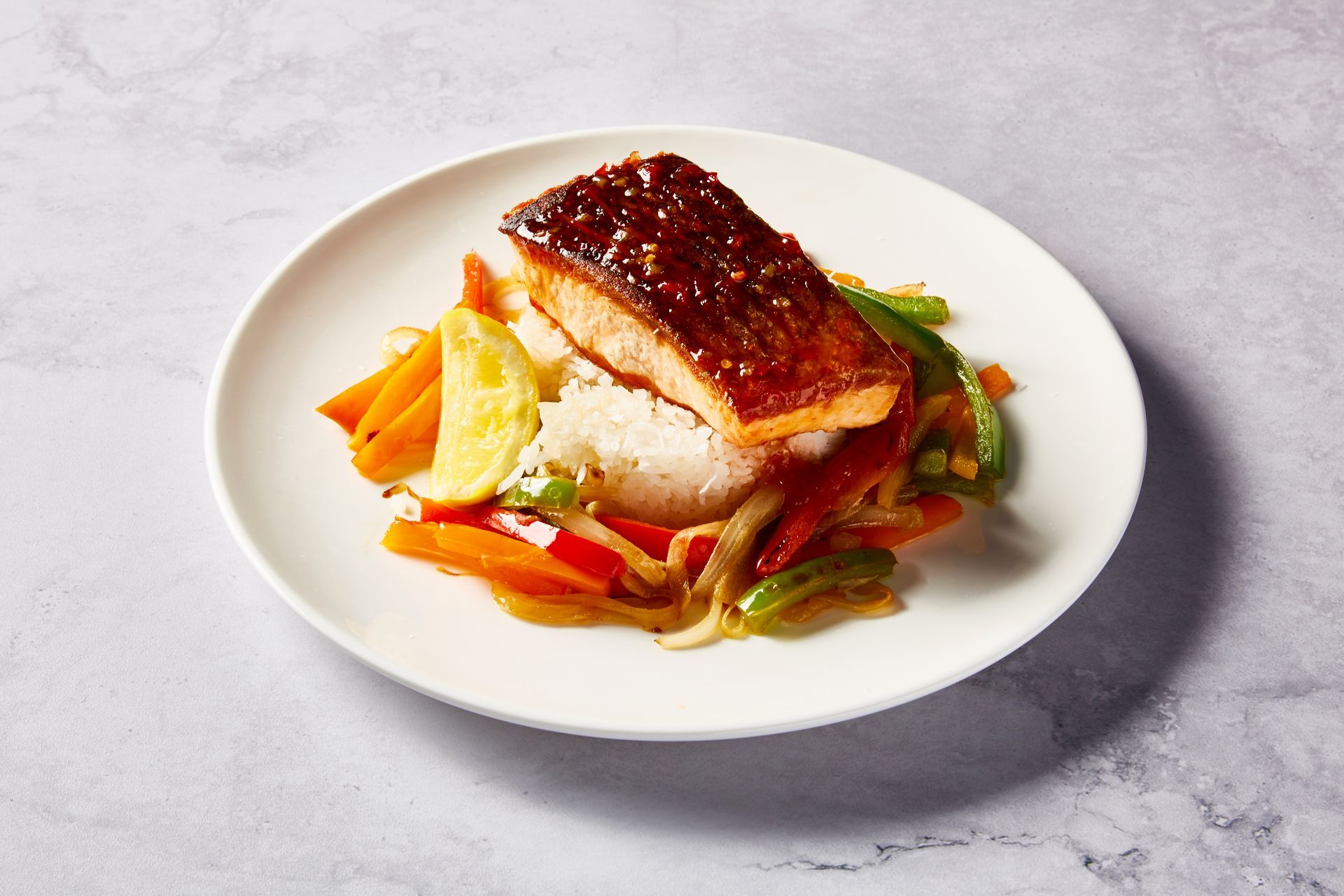 A white plate topped with a piece of salmon and vegetables.
