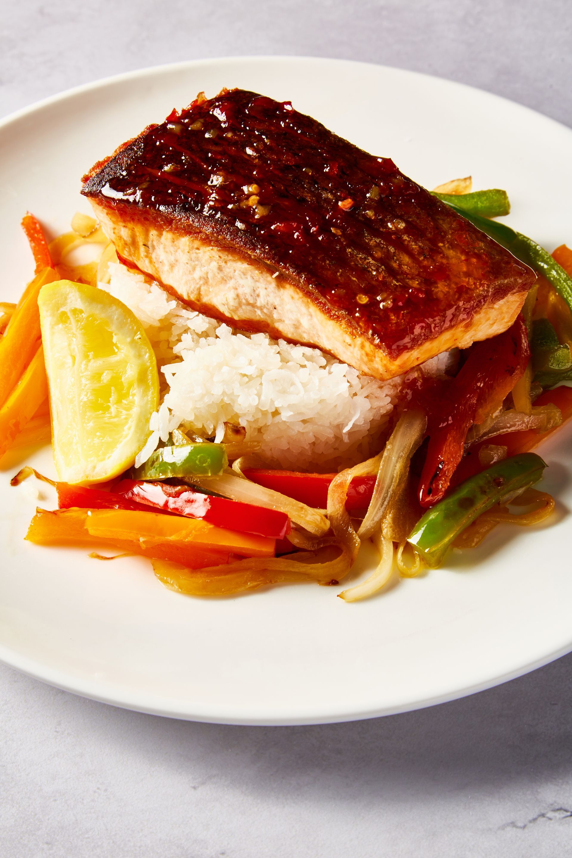 A white plate topped with rice , meat and vegetables.