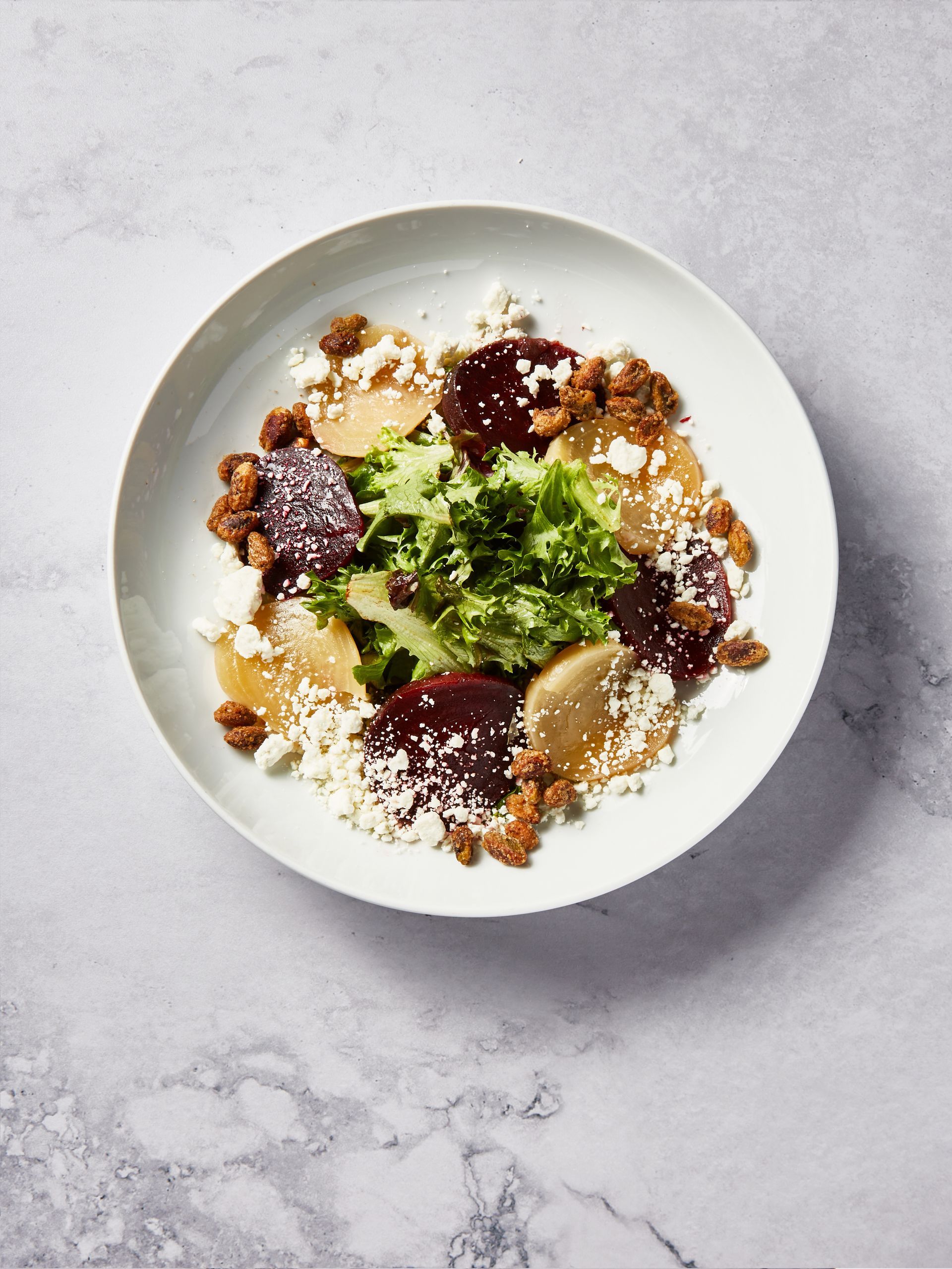 A white plate topped with a salad on a table.
