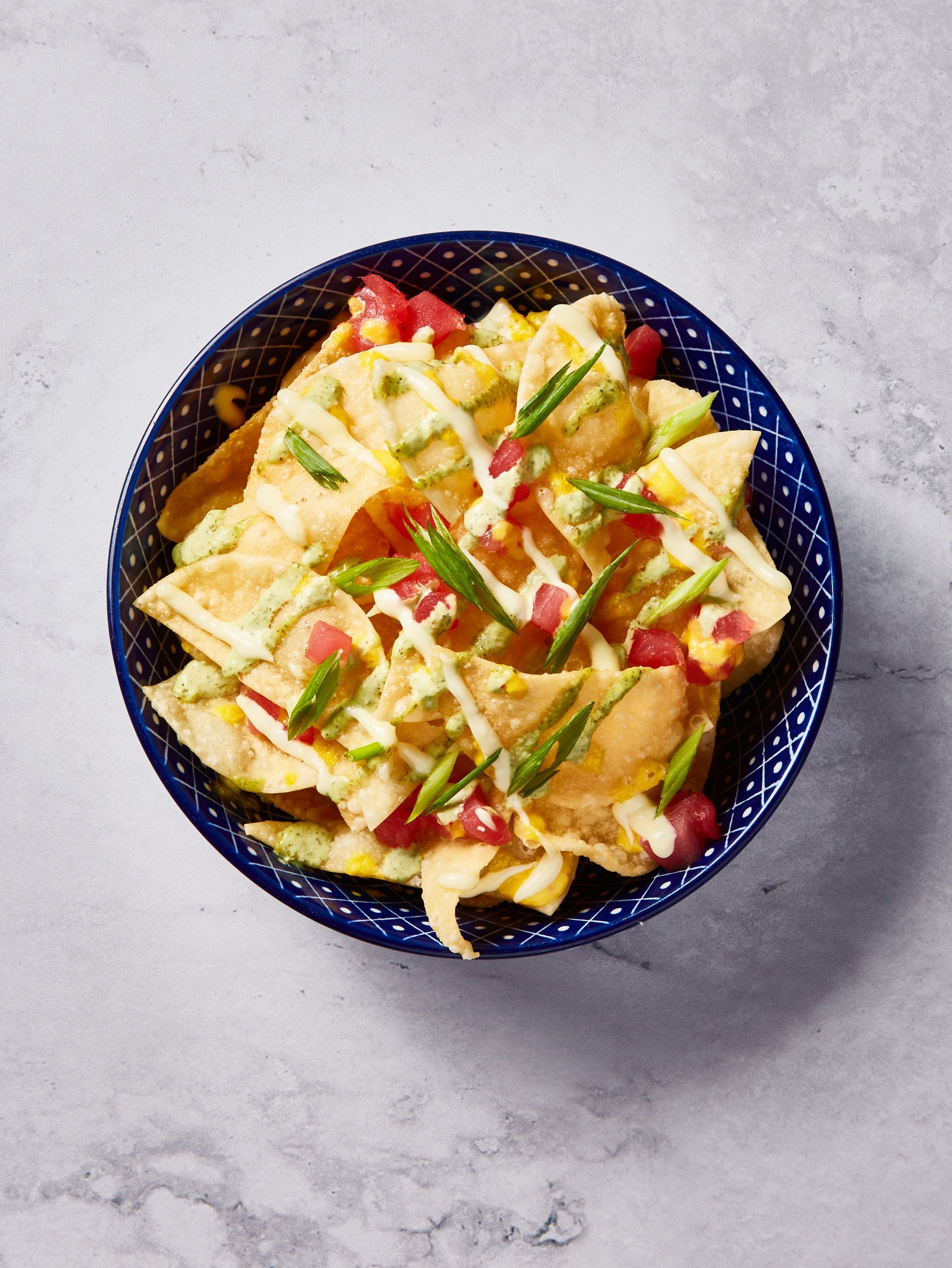A bowl of nachos with sauce and vegetables on a table.
