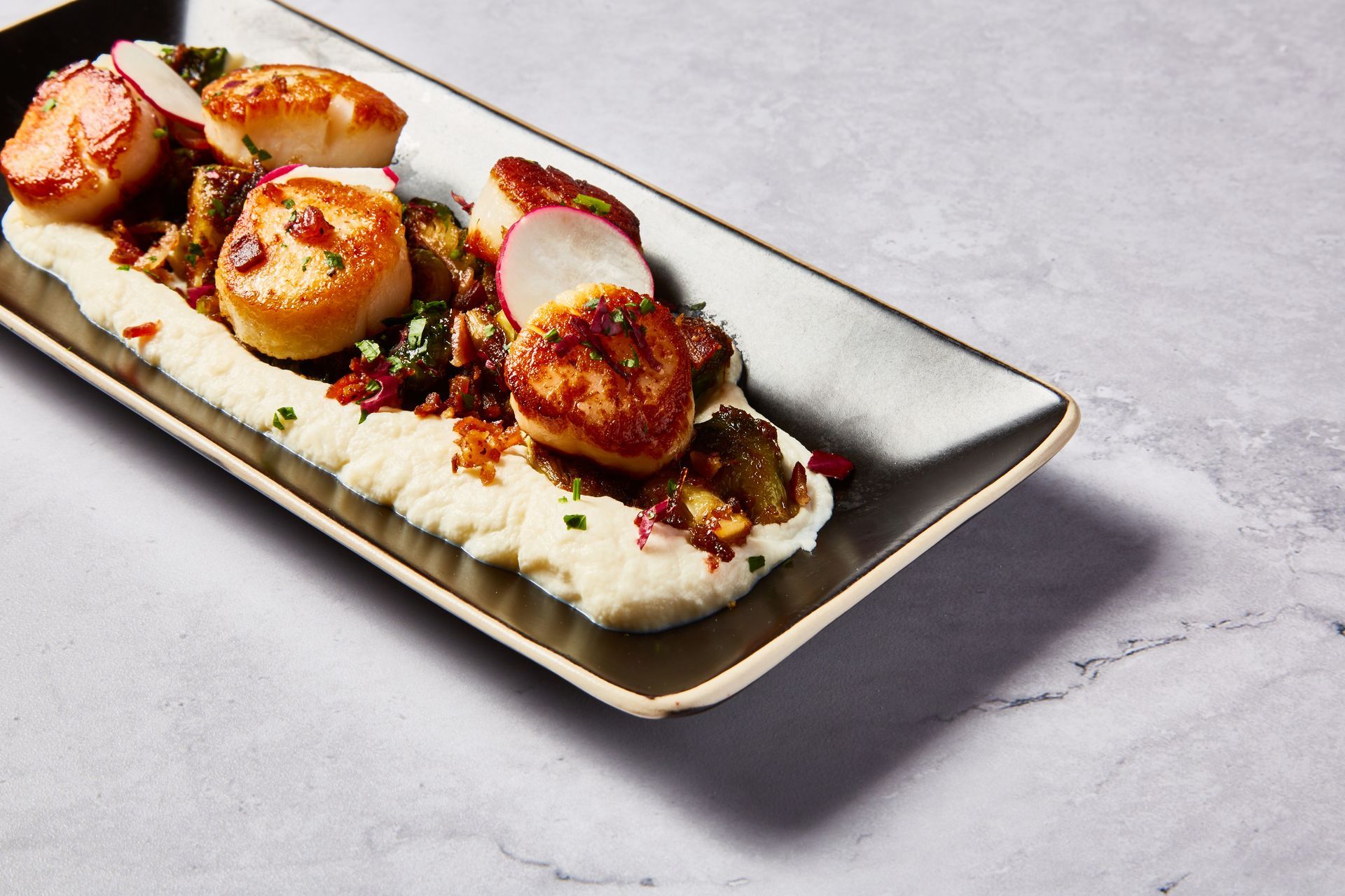 A plate of food with scallops and mashed potatoes on a table.