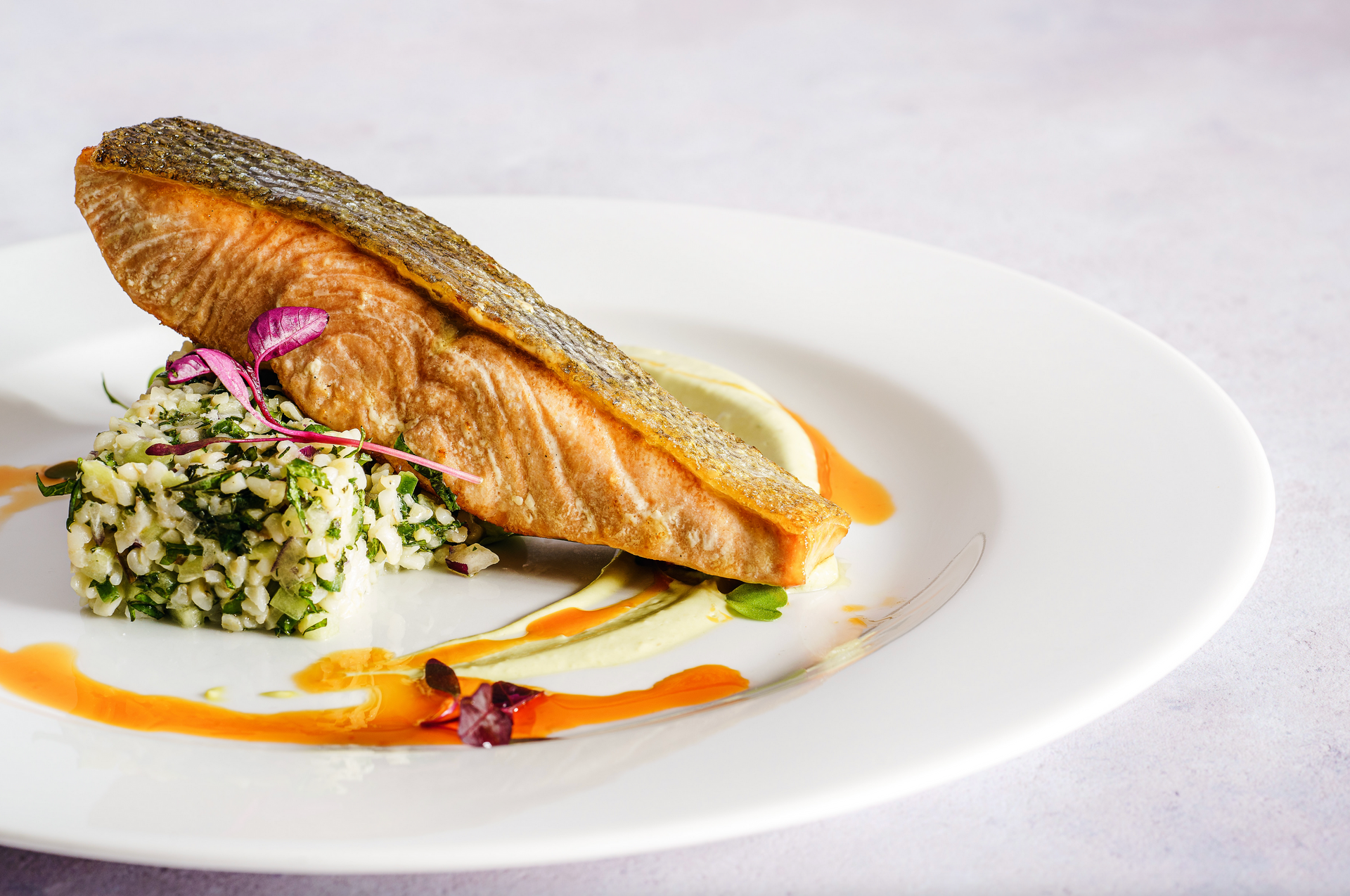 A white plate topped with a piece of salmon and rice.