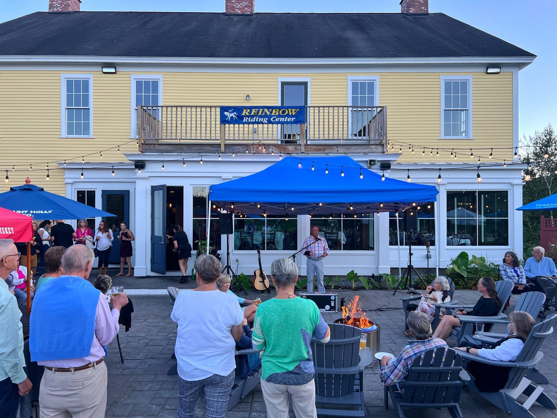 A group of people are gathered in front of a yellow building.